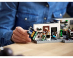 Hands placing a LEGO hair salon counter piece into the Queer Eye Fab 5 Loft set, featuring minifigures and brick-built furniture.