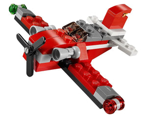 A red and gray LEGO Creator 31013 Red Thunder airplane with a black propeller, green wingtip light, and red tail light.