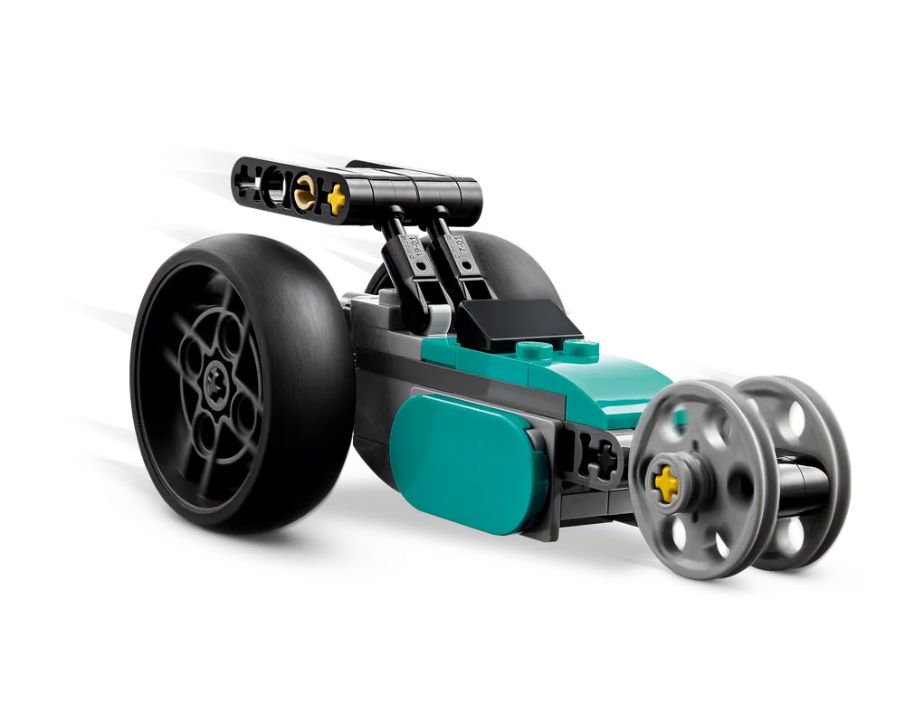 Teal and black LEGO dragster car with a large rear wheel and smaller front wheels, shown in motion on a white background.