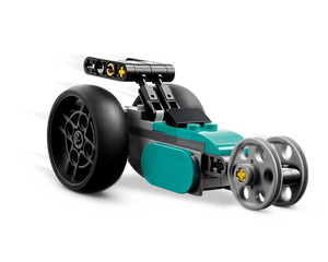 Teal and dark gray LEGO Creator 31135 dragster-style car with large rear wheels and small front wheels, showing motion blur.