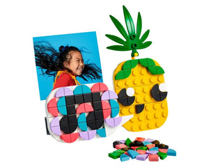 LEGO Dots photo holder with colorful tiles, a girl's photo, a pineapple mini board, and loose tiles.