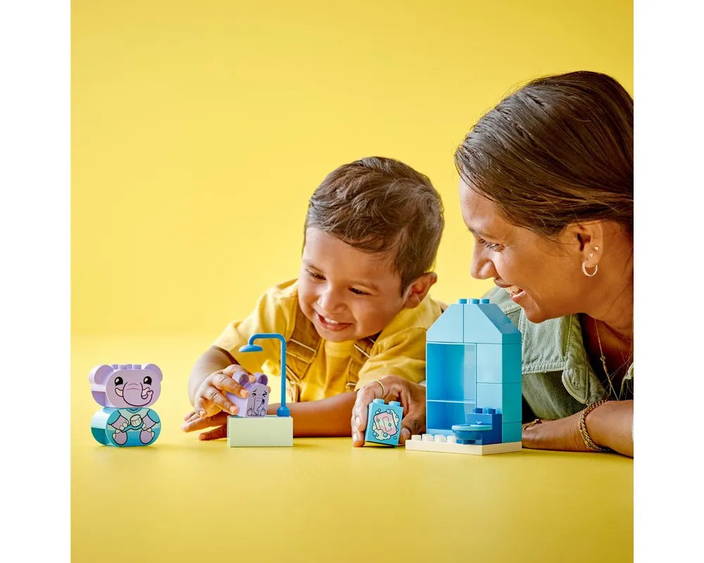 Child and adult playing with LEGO DUPLO 10413 Daily Routines Bath Time set, featuring elephant figures and blue bath structure.