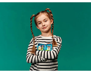 Young girl with pigtails holding two open blue LEGO Friends cubes, showing mini-dolls and play scenes against a teal background.