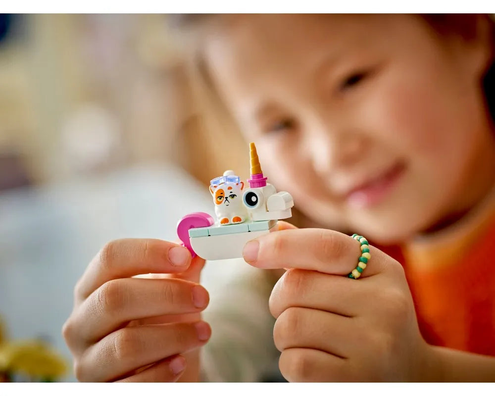 Close-up of a child's hands holding a LEGO Friends unicorn cat character with goggles.