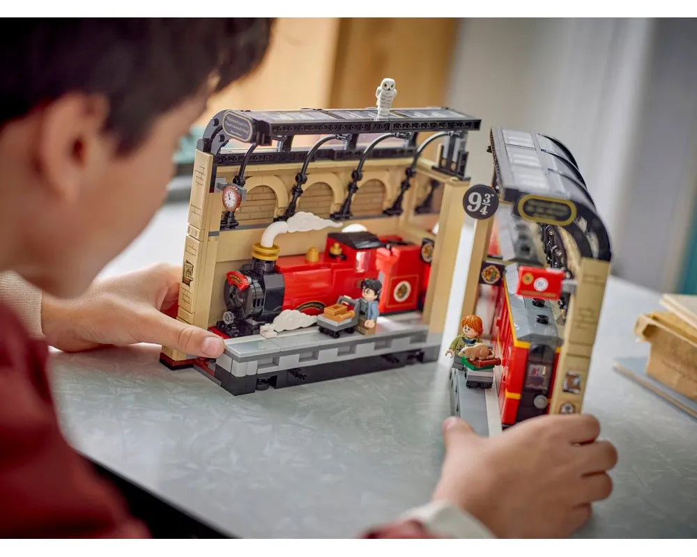 Child playing with LEGO Harry Potter 76450 Hogwarts Express Book Nook featuring Platform 9 3/4, train, and minifigures.