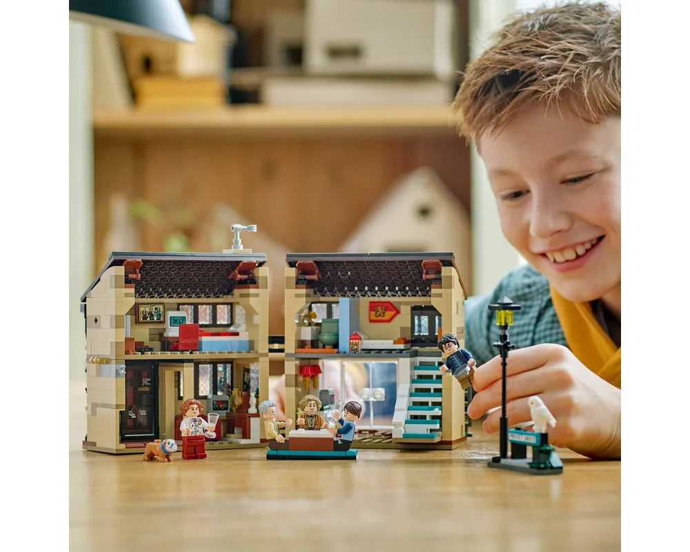 Smiling boy plays with LEGO Harry Potter 76451 Privet Drive: Aunt Marge's Visit set, showing house interior and minifigures.
