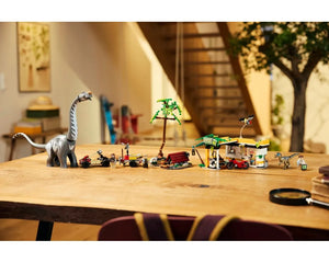 LEGO Jurassic World 76973 set: Brachiosaurus, raptor, minifigures, vehicles, gas station, and jungle scene on a table.