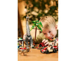 LEGO Jurassic World 76973: A boy plays with a Titanosaurus, raptor, camp, vehicles, and minifigures on a table.