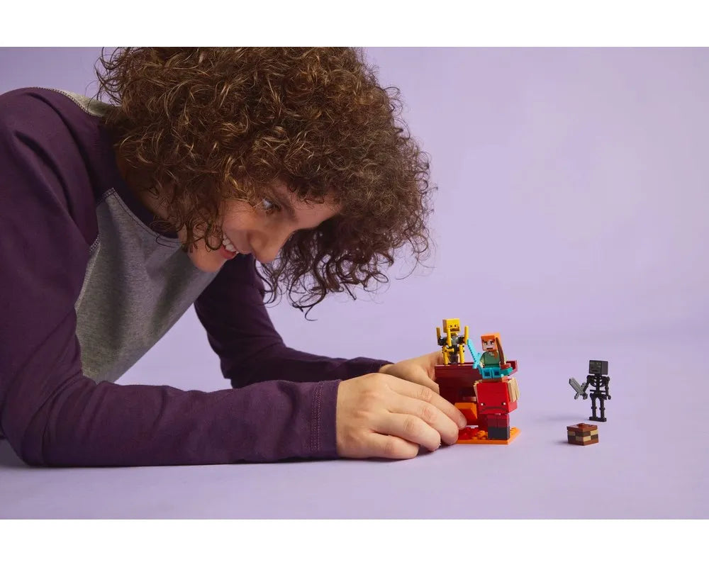Person with curly hair smiles, playing with LEGO Minecraft 21266 The Nether Lava Battle set on a purple surface.