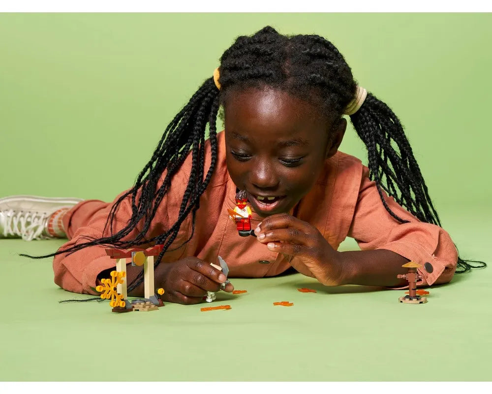 Young girl playing with LEGO Ninjago 71730 Epic Battle Set, holding Kai minifigure and other small builds.