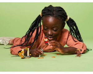 Young girl playing with LEGO Ninjago 71730 Epic Battle Set, holding Kai minifigure and other small builds.