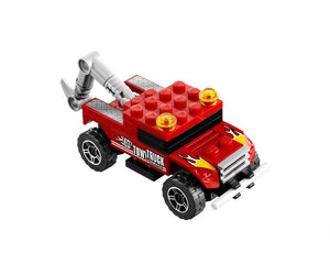 Red LEGO toy tow truck with grey crane, yellow warning lights, and flame decals on its hood, on a white background.