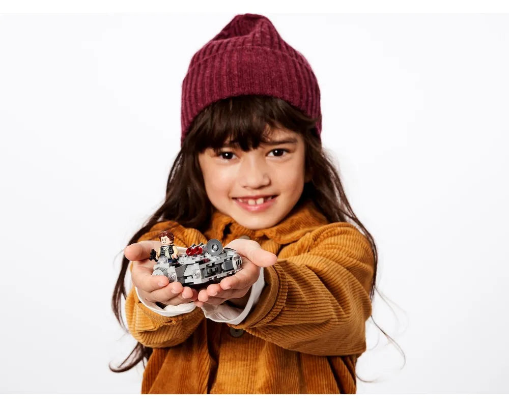 A smiling child holds a LEGO Star Wars 75295 Millennium Falcon Microfighter, with Han Solo minifigure, in their hands.