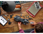 Person building a LEGO Batman Forever Batmobile with digital instructions on a wooden desk.