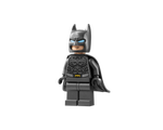 Dark grey LEGO Batman minifigure with blue eyes, a cape, and a yellow bat symbol on its chest, standing upright.