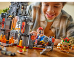Smiling child plays with LEGO Super Mario Bowser's Castle. Features LEGO Mario in a kart, Bowser, and Thwomp.