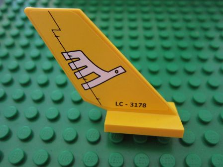 Yellow LEGO tail shuttle piece with a white airline bird logo and 'LC - 3178' text, sitting on a green baseplate.
