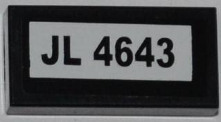 Black LEGO 1x2 tile with a white sticker featuring the text 'JL 4643'.