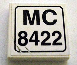 White LEGO 2x2 tile featuring a sticker with 'MC 8422' in a black rounded rectangle frame. Minor sticker wear visible.