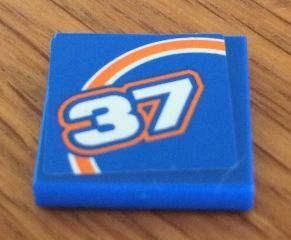 Blue LEGO 2x2 tile with orange bow and white number 37 pattern, from Set 8163.