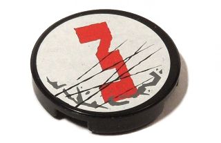 Close-up of a black, round LEGO 2x2 tile with a white top, featuring a red number 3, dark bluish-gray splotches, and black scratches.